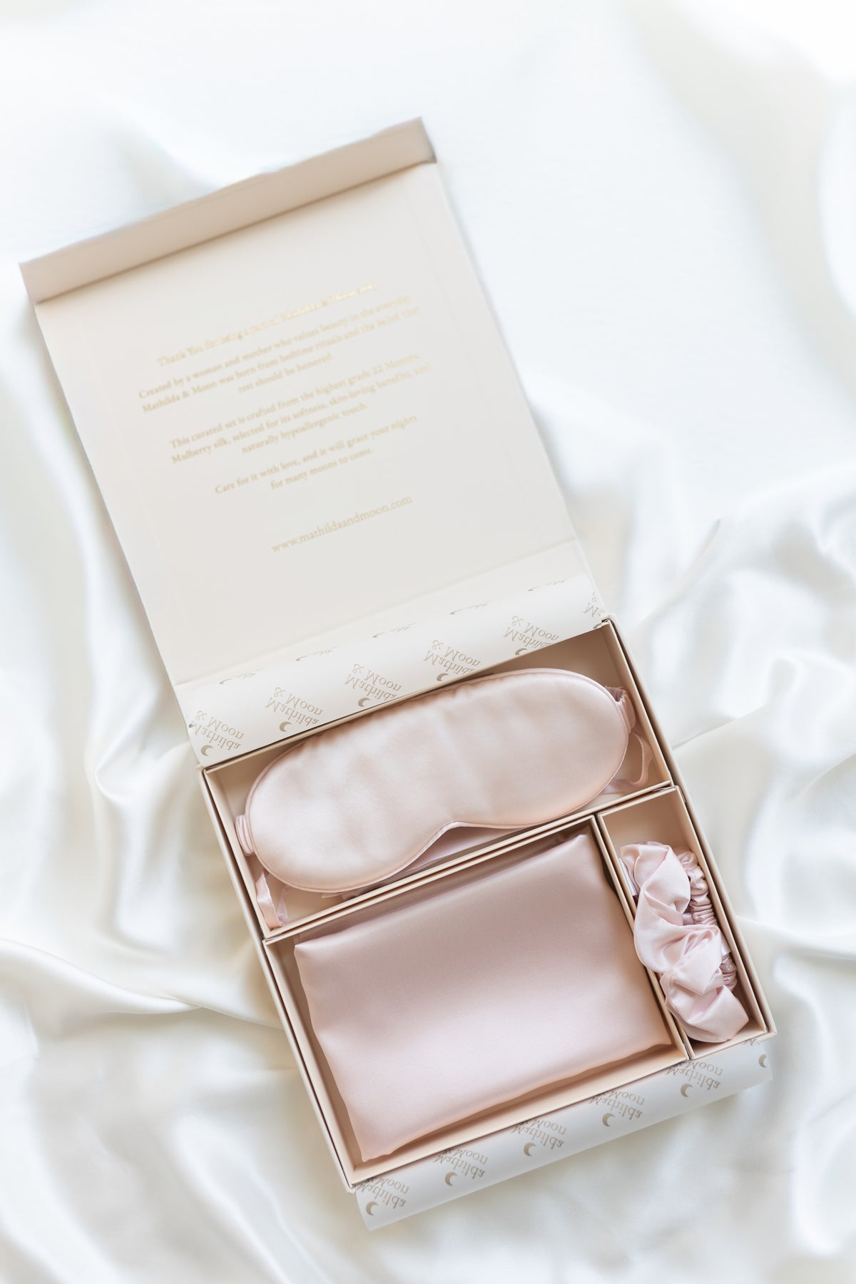 Pink Silk gift set with sleep mask, pillowcase and matching silk scrunchies in a gift box on white background.